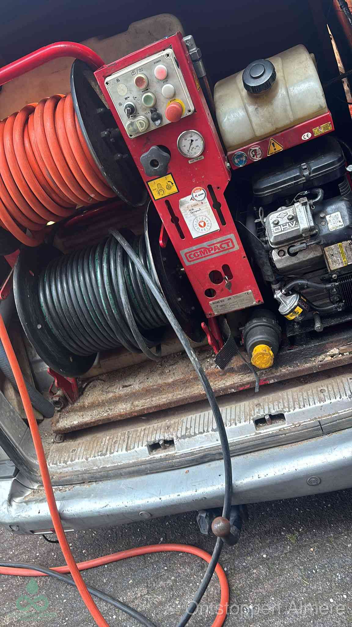 Een rood hogedruk-rioolreinigingstoestel in de laadbak van de bedrijfsbus, apparatuur voor een hardnekkige afvoerverstopping in Almere