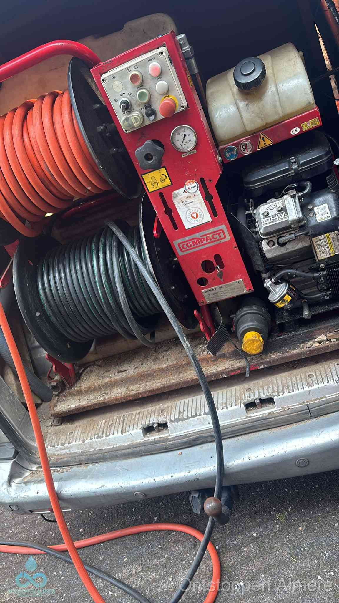 Een rood hogedruk-rioolreinigingstoestel met slangen in de laadbak van de bedrijfsbus, apparatuur voor een hardnekkige wc-verstopping in Almere