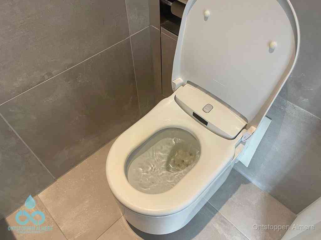 Een toiletpot vol troebel water met drijvend papier en restanten, de meest voorkomende oorzaak van een verstopte wc in Almere