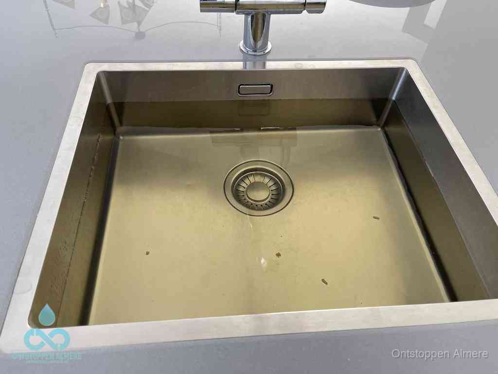 Stilstaand water in een rvs spoelbak dat niet wegloopt, een duidelijk signaal van een gootsteenverstopping in Almere
