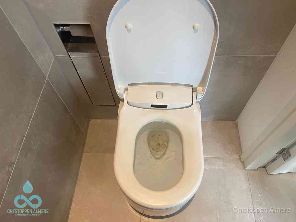 Een wit hangtoilet waarin een prop wc-papier op het water blijft drijven, een duidelijk signaal van een verstopte wc in Almere