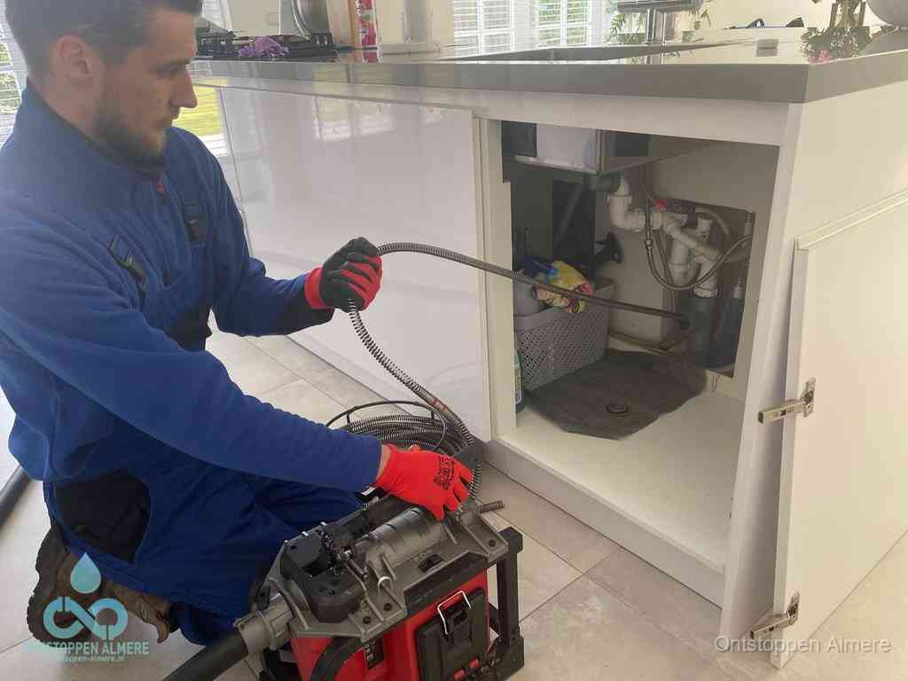 Een monteur reinigt de keukenafvoer grondig met een veermachine om terugkerende gootsteenverstoppingen te voorkomen in Almere