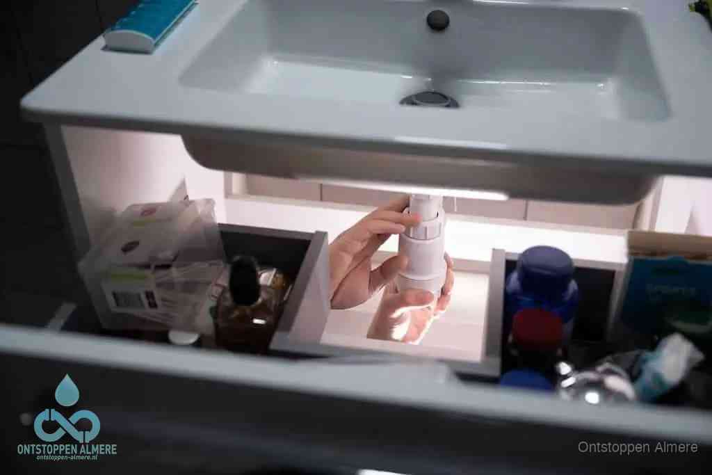 Een pompfles met zeep boven een wastafel in de toiletruimte, de warm water en afwasmiddel-methode om de wc te ontstoppen in Almere