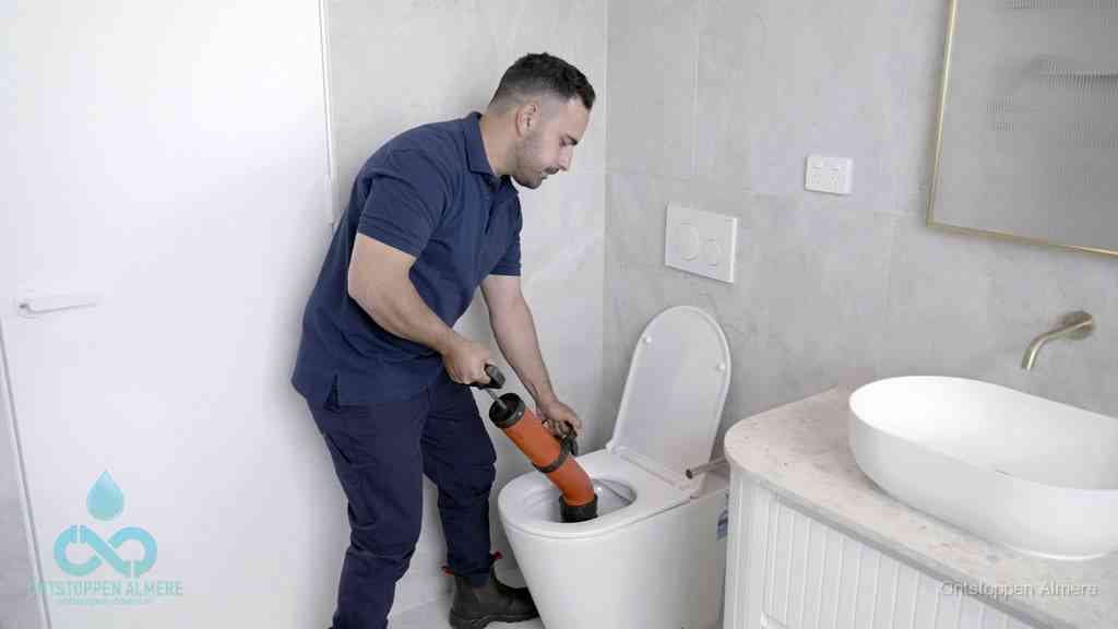 Een monteur gebruikt een handmatige perspomp (toiletontstopper) op een wandcloset tijdens het professioneel wc ontstoppen in Almere